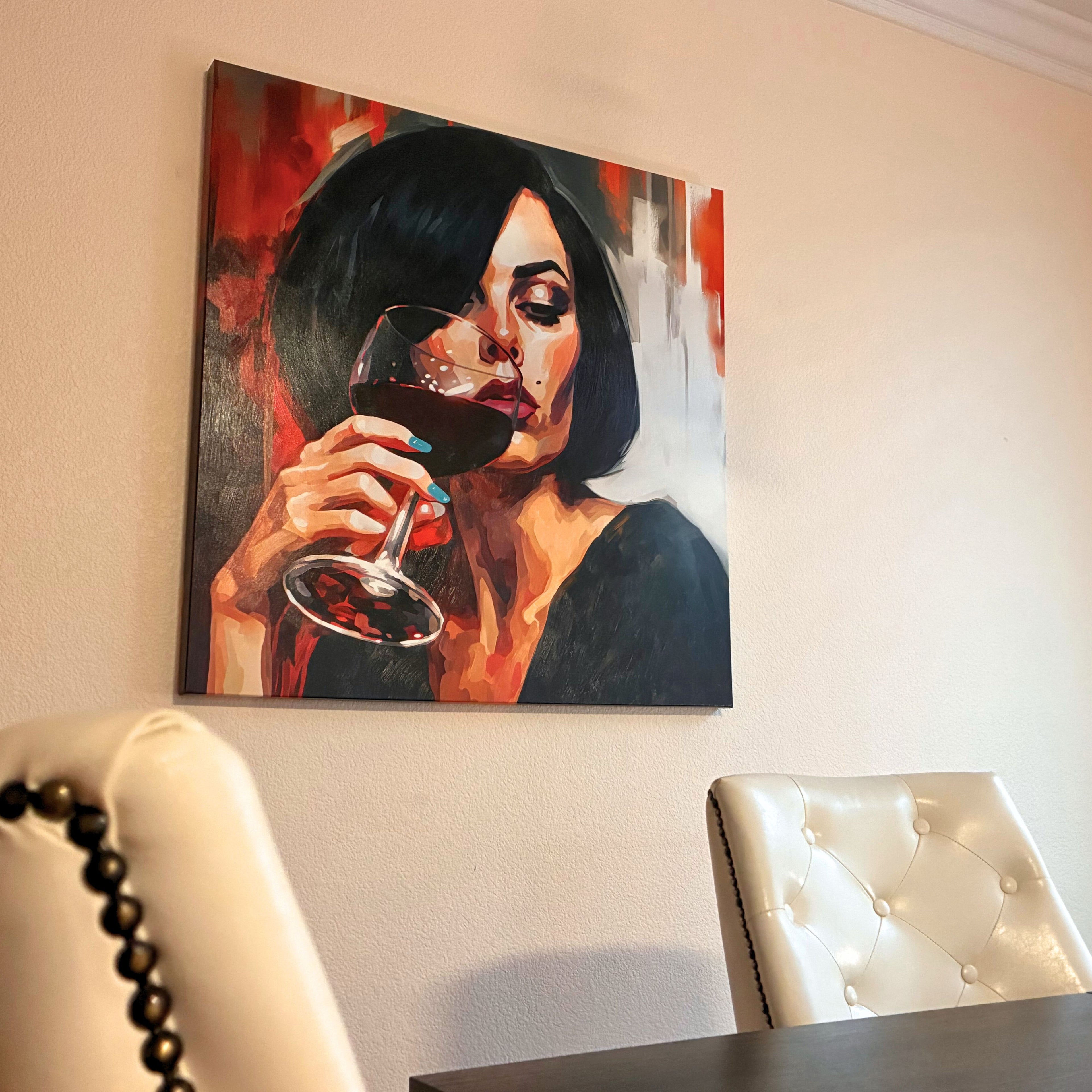 Painting of a woman holding a glass of red wine on a wall above a table.